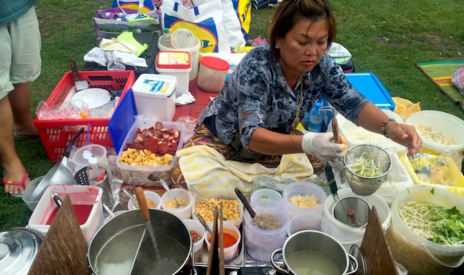 A woman serving food at the Thai food market in Berlin